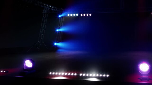 Bright lights illuminate the stage at a venue. The area is dark except for the colorful beams from the lights. This scene captures the excitement before a performance begins.