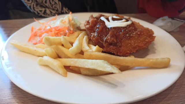 A delicious serving of chicken cordon bleu accompanied by crispy French fries, offering a classic combination of tender chicken, melted cheese, savory filling, and golden fried potatoes in an appetizi