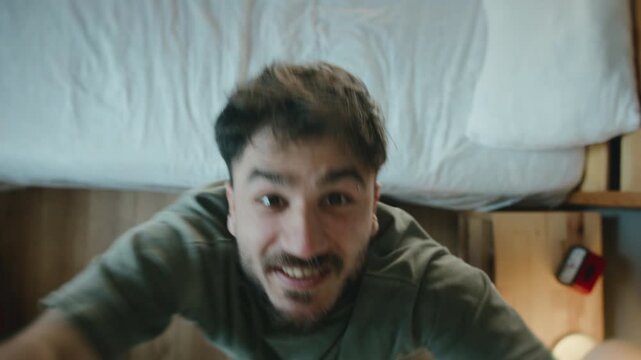 Man dancing energetically in bedroom looking at camera, funny morning mood