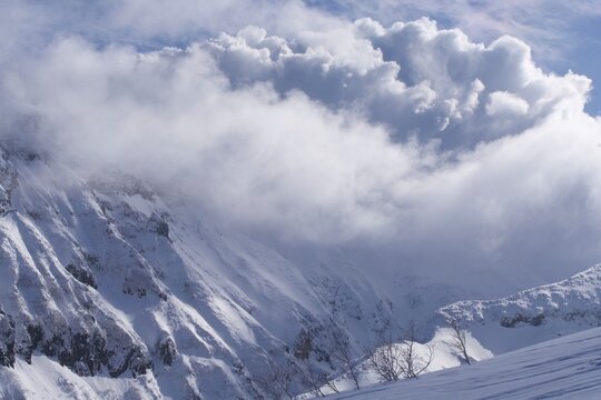 Snow-covered volcanic wall with clouds surging upward, Hokkaido, Japan