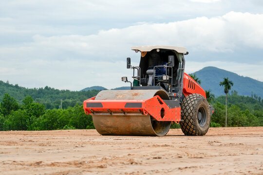 Heavy machinery flattens soil at an outdoor development location during the day as part of building site preparation work