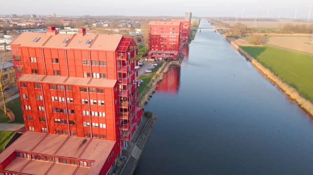 Aerial view of the distinctive red residential buildings in the Regenboogbuurt neighborhood along a canal in Almere, Flevoland, Netherlands.