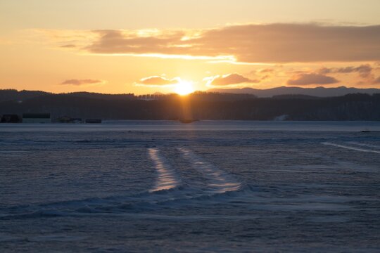 Low winter sun over rows of snow ripples stretching across a field, Hokkaido, Japan
