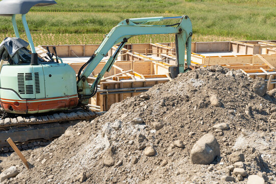マイホームの建築現場の基礎工事と土砂の掘削作業現場とショベルカー