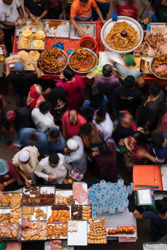 Dhaka, Bangladesh - 09 April 2024: Aerial view of Chak Bazar Iftar Market with crowds of people buying traditional food items, vibrant stalls, and various snacks displayed on tables.
