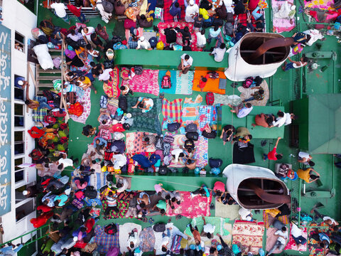 Dhaka, Bangladesh - 25 August 2026: Aerial view of passengers sitting on mats on the deck of a ferry, preparing to travel home for the Eid holiday.