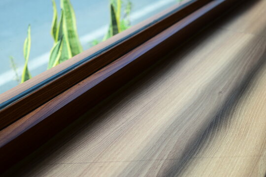 modern wooden window frame sill with green plant outside