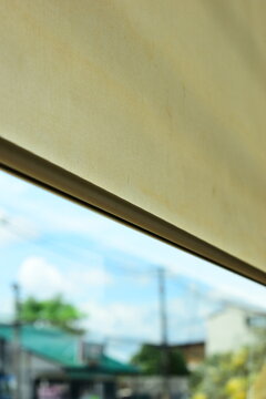 beige window roller shade bar with blurred outdoor city view