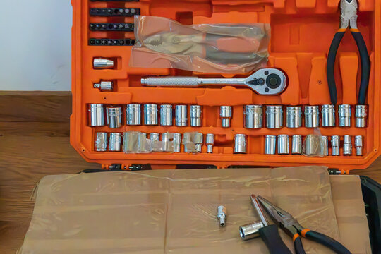 Macro close-up of an open orange tool box containing a socket wrench set
