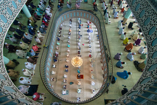 Dhaka, Bangladesh - 21 August 2020: Aerial view of Baitul Mukarram National Mosque with worshippers praying inside, featuring architecture, a large chandelier, and rows of people on prayer mats.