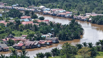Fototapeta premium Traditional stilt houses along a riverbank in a tropical village landscape in South Kalimantan