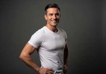 Obraz premium Portrait of a fit smiling man in a white tshirt against a grey background