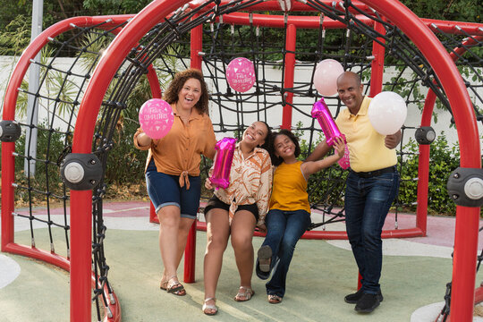 Family celebrating birthday with balloons at playground