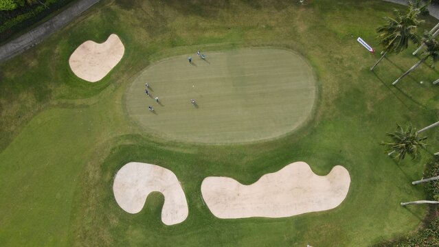 Kecamatan Kebayoran Lama, Indonesia - 23 June 2022: Aerial view of Pondok Indah Golf Course with golfers on the green, sand bunkers, and palm trees.