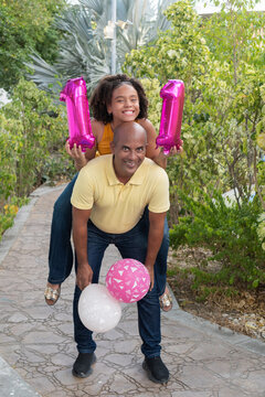 Father carrying daughter celebrating 11th birthday outdoors