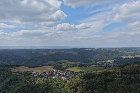 Ehlscheid, Rhineland-Palatinate, Germany - 23 August 2026: Aerial view of the village of Ehlscheid nestled in the forested hills under a cloudy sky.