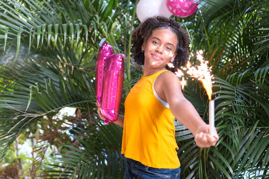 Girl celebrating birthday with sparkler and number balloon