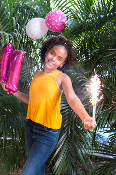 Young girl celebrating birthday holding sparkler and balloons