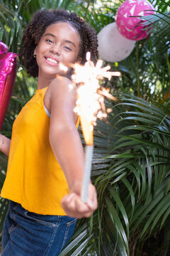 Young girl celebrating birthday holding sparkler outdoors