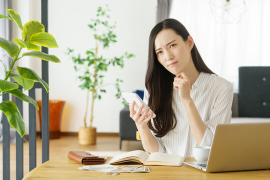 電卓を持って困った顔をするミドルエイジの日本人女性