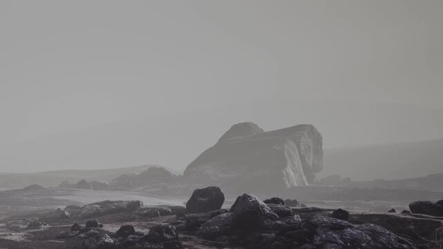 A vast and rocky area is shown with large boulders scattered across the ground. Thick fog covers the scene, making it hard to see far. Hills can be seen in the distance.