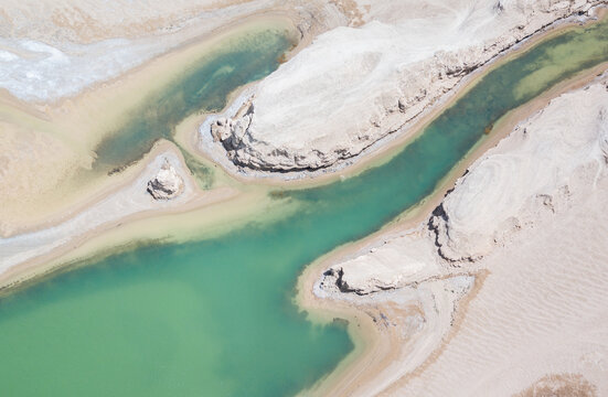 Unique water-covered yadan landforms stand in clear turquoise water under a bright blue sky, surrounded by arid desert terrain.