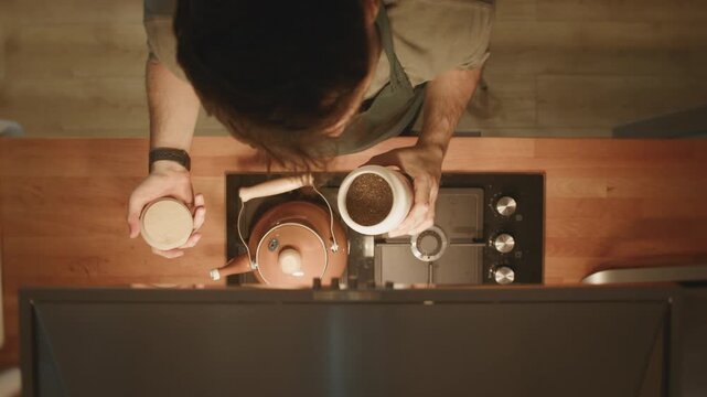 Top view of man smelling aromatic dry tea leaves before brewing in copper kettle on stove