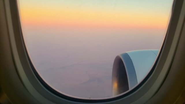 Beautiful view from airplane window featuring sunset sky over desert landscape during flight.