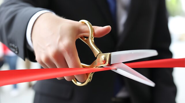 A professional business person cutting a red ribbon with gold scissors for a grand opening ceremony inauguration event