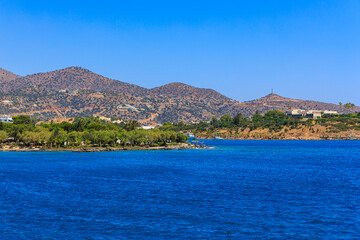Fototapeta premium Coastal view with deep blue water, greenery, and rocky hills