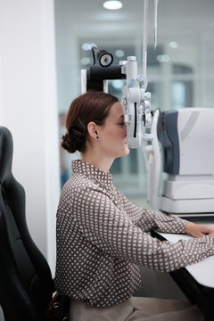 White female patient eye exam with phoropter equipment, vision and eyesight improvement by expert optometrist woman, diagnostic for eyeglasses lens, professional technology services in optical clinic.