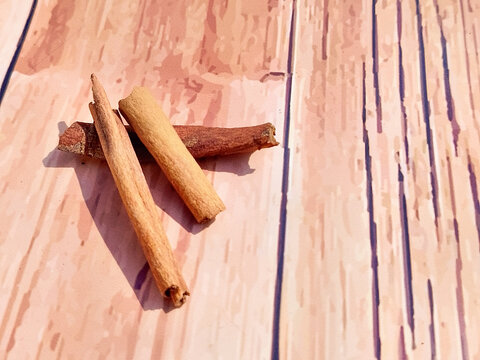 Three organic cinnamon sticks spice placed on a light pinkish wooden plank background for food and drink concepts