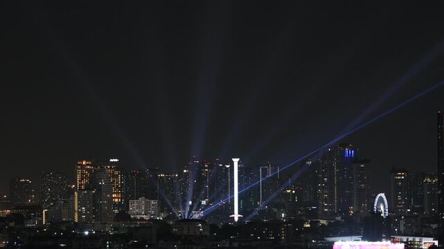 The video background features a fast-moving sky and clouds in the capital city. This beautiful time-lapse video showcases the illuminated condominium buildings of Bangkok at dusk.
