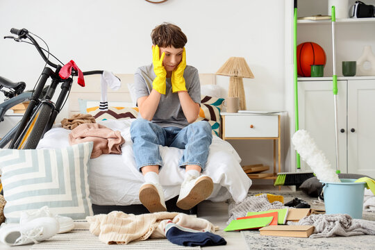 Overwhelmed by household chores, young person feeling stressed about cleaning a messy room and tidying up