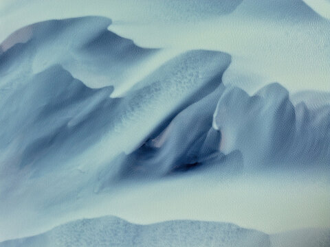 Aerial view of the snow-covered slopes of Naustavik Mountain with rugged terrain and icy textures in Husavik, Nordurthing, Iceland.