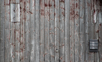 Weathered grey vertical wood siding texture with remnants of peeling red paint © Jason