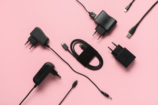 Composition with modern power adapters and different cables on pink background