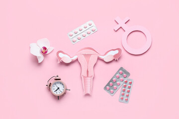 Naklejka premium Paper uterus with orchid flower, alarm clock, symbol of woman and pills on pink background