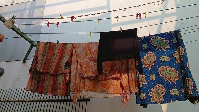 Woman Taking Dry Clothes Off a Clothesline After Air Drying Outdoors