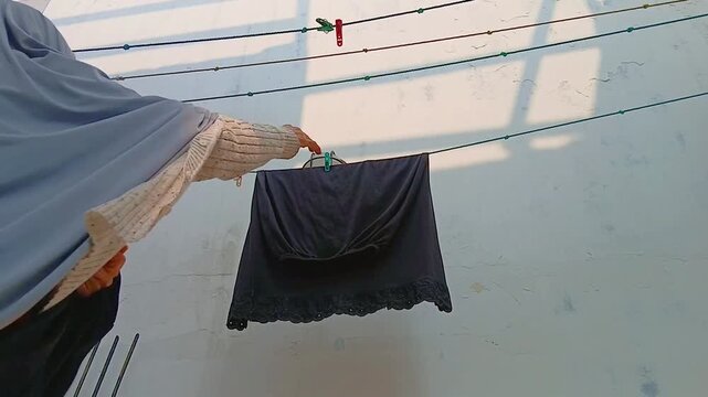 Woman Taking Dry Clothes Off a Clothesline After Air Drying Outdoors