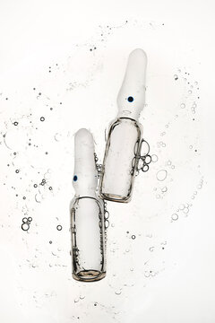 Two transparent glass ampoules floating in liquid with air bubbles
