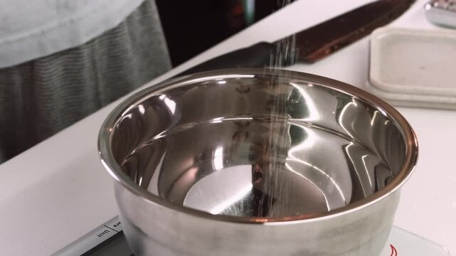Cooking food. Sugar recipe measuring. Chef pouring white culinary powder to metal bowl scale. Professional confectionery workflow.
