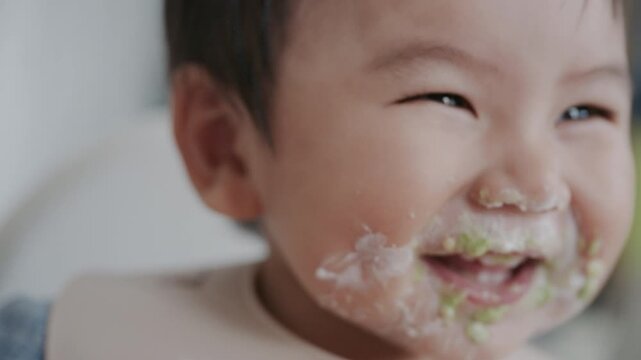 Asian baby boy self feeding sweet corn using baby led weaning method at home.	
