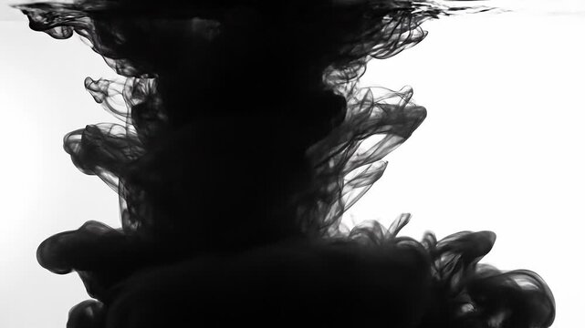 Black ink swirling in water creating abstract shapes with white background artistic fluid motion