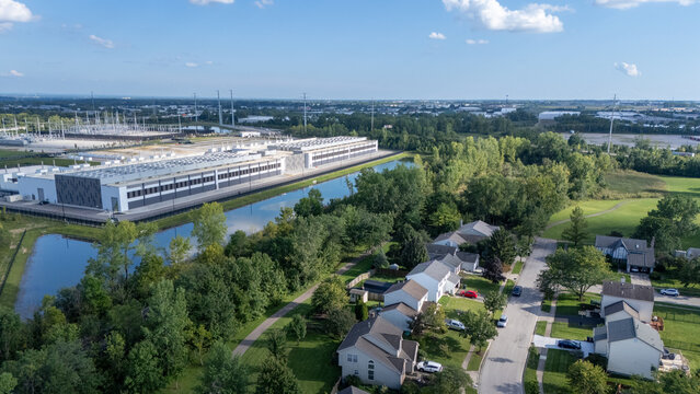 Hilliard, Ohio, United States - 21 August 2026: Aerial view of the Amazon data center with industrial buildings, rooftop cooling units, a pond, and a nearby suburban neighborhood.