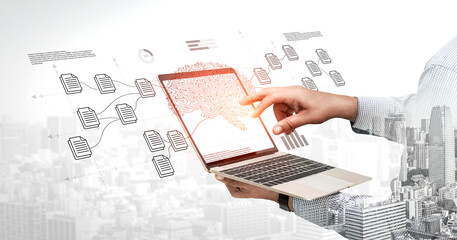 A hand interacts with a laptop displaying data graphics and flow diagrams against a cityscape. This...