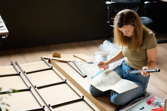 Woman reading instructions while assembling shelf at home