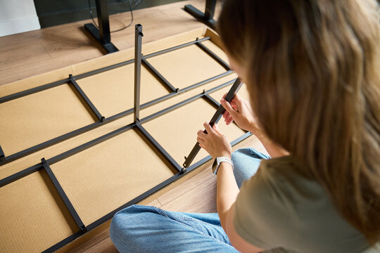 Woman Connecting Parts of a Metal Shelving Unit at Home