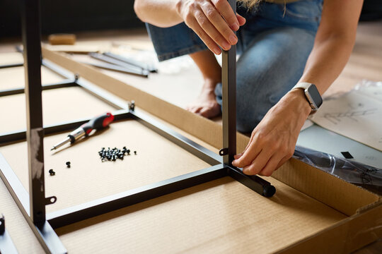 Woman assembling flat pack shelving unit at home