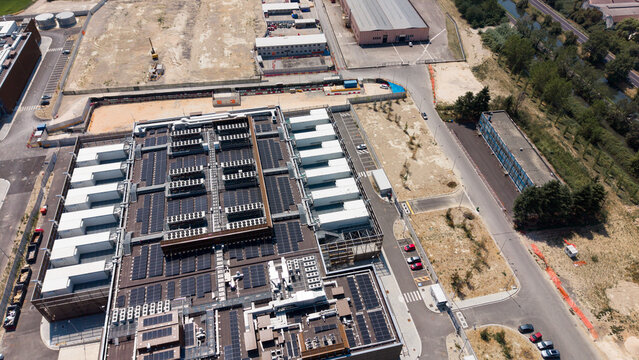 Aerial view of Stack Infrastructure MIL04 Campus with rows of cooling units and solar panels on the roof, surrounded by industrial grounds in Vellezzo Bellini, Lombardy, Italy.